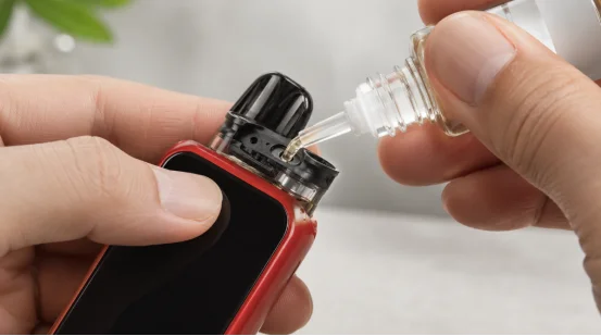 Person refilling a vape pod with e-liquid